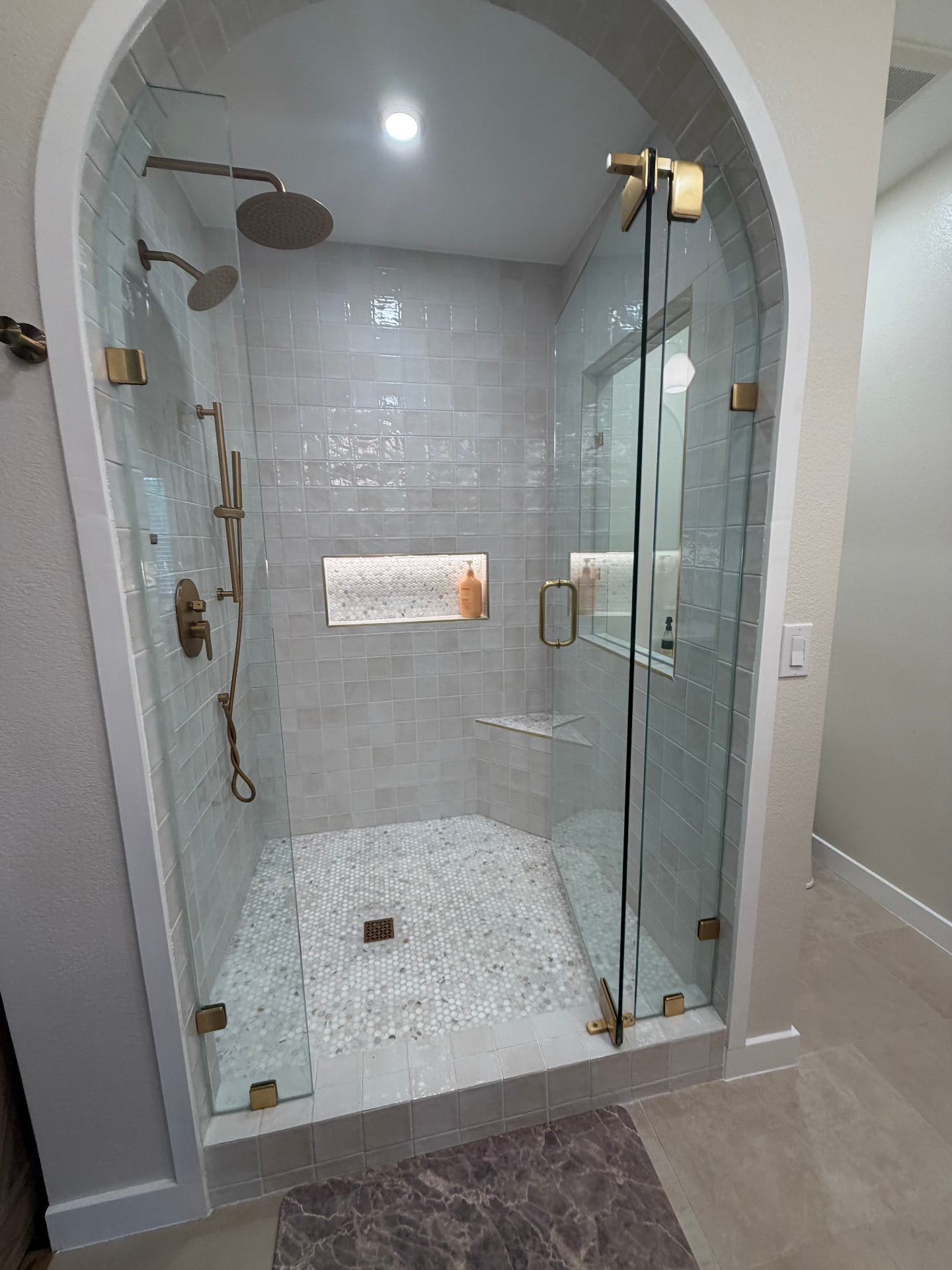Custom arched walk-in shower with tile and brass fixtures