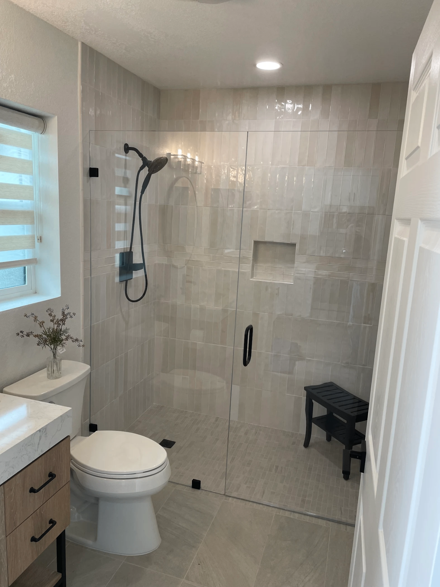 Modern walk-in shower with glass enclosure, vertical tile, and built-in niche